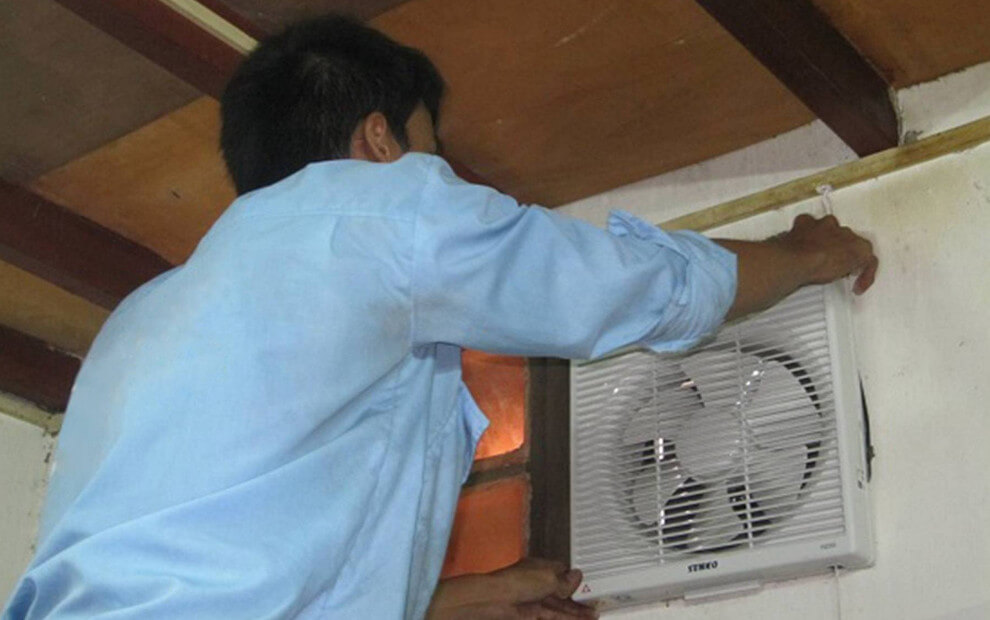 công nhân đang khoan tường lắp quạt hút vuông